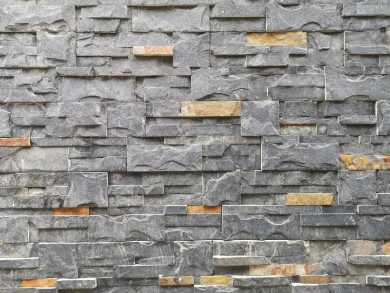 A close-up of a textured stone wall made of slate and granite bricks for architectural design.